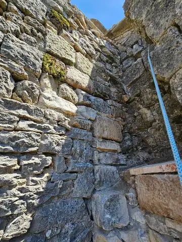 Mur de pierre ancien avec corde d'accès tendue le long du parement