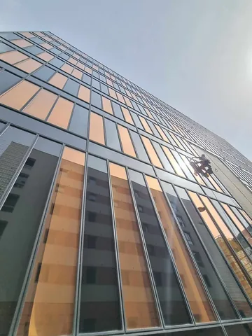 Cordiste le long d'une façade vitrée d'immeuble de grande hauteur