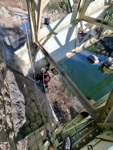 Cordiste sous un tablier de pont, au-dessus de l'eau